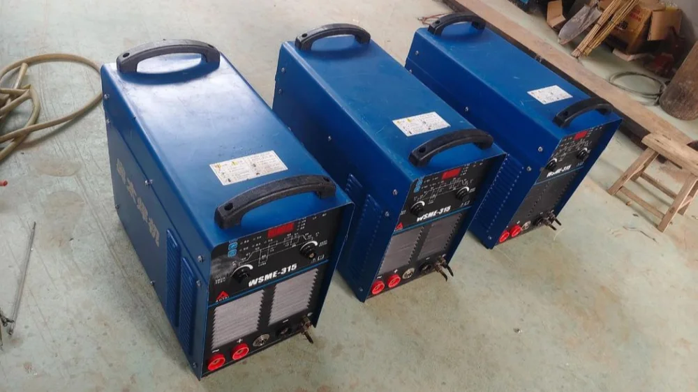 Three blue industrial inverter TIG welding machines on workshop floor, durable metal casing with clear control panels, vents and terminals