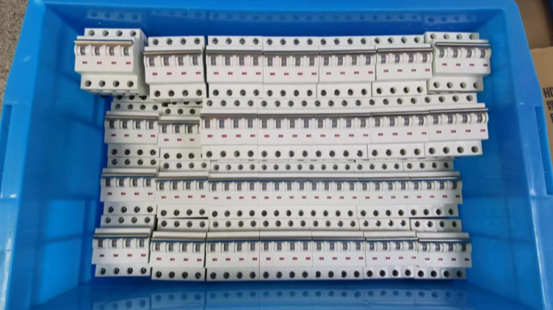 A blue plastic storage bin neatly packed with a full box of miniature circuit breakers, showing a sufficient stock of electrical components.