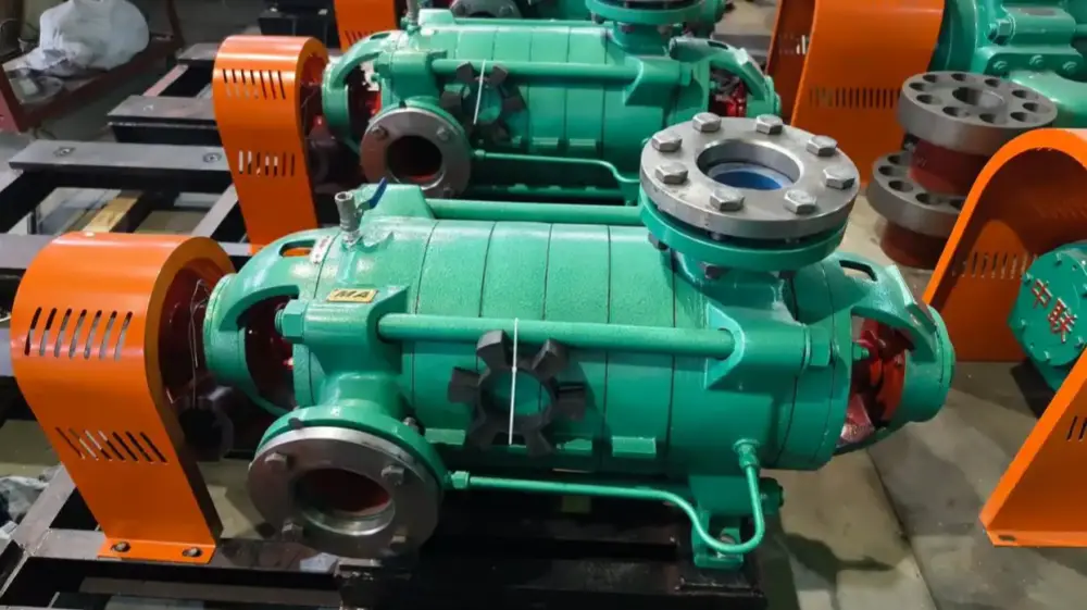 Green multistage centrifugal pump with orange protective cover and metal flange connections in a workshop, precise casting and coupling visible
