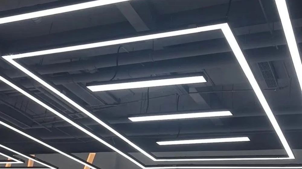 Modern industrial ceiling with linear LED lighting fixtures, featuring white rectangular and straight light bars against a black exposed ceiling, creating a bright minimalist commercial space lighting effect.