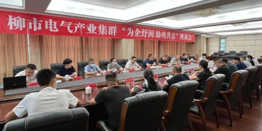 Attendees seated around a long conference table in a meeting room, with a large red banner above displaying text about helping enterprises and supporting people with disabilities