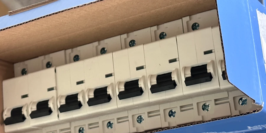 A row of white miniature circuit breakers with black switches packed neatly inside a blue cardboard box