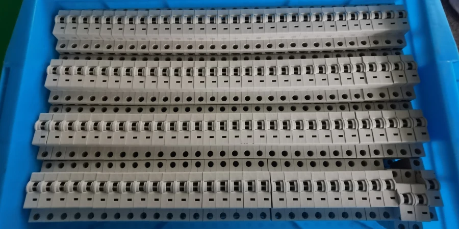 Rows of gray circuit breaker shells arranged inside a blue plastic tray.