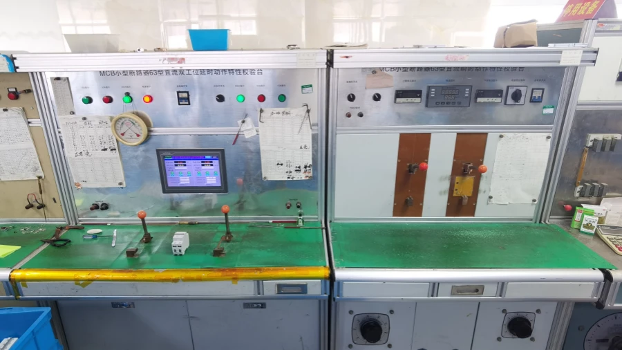 Two calibration stations with control panels, displays, and levers on green workbenches, used for instantaneous and long-delay testing of miniature circuit breakers.