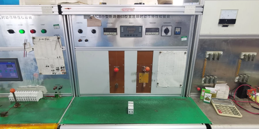 A test bench for MCB instantaneous trip testing, featuring control dials, a digital display, red buttons, and a miniature circuit breaker placed on the green desk, with a calculator and test equipment nearby.